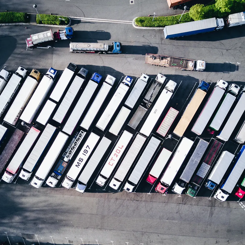 Widok z góry na plac z zestawami ciężarowymi i infrastrukturą transportową